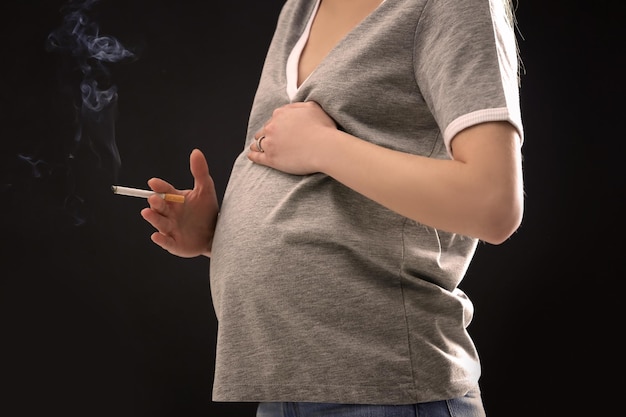 Mujer Embarazada Fumando Cigarrillo Sobre Fondo Oscuro Foto Premium