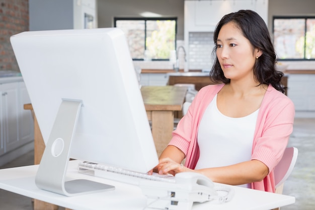 Mujer embarazada seria que usa la computadora en casa | Foto ...