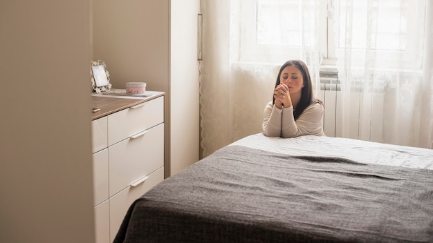 Mujer emocional diciendo una oración en casa Foto gratis