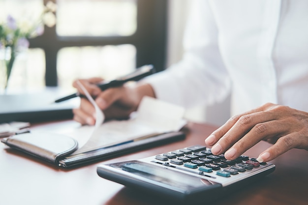 Mujer con facturas y calculadora. mujer que usa la calculadora para calcular cuentas en la tabla en oficina. Foto Premium 