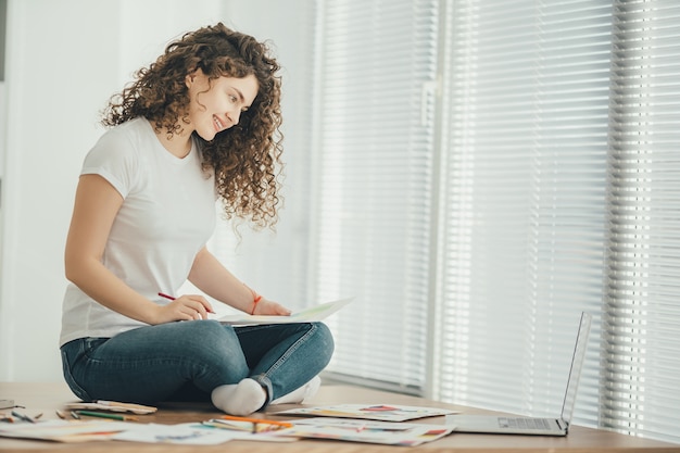 La Mujer Feliz Sentada En La Mesa Y Dibujando En El Papel Foto Premium