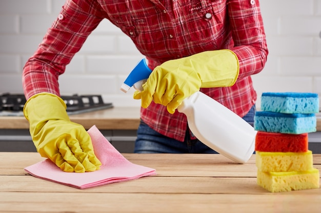 La mujer en guantes protectores amarillos que limpian la