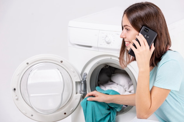 Mujer Hablando Por Telefono Mientras Lava La Ropa Foto Gratis