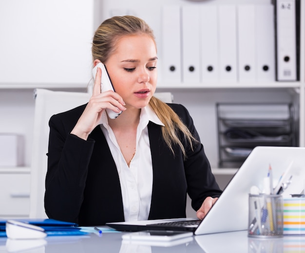 Mujer hablando por teléfono en la oficina | Foto Gratis