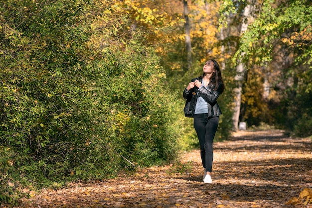 Mujer hermosa joven camina por el callejón de un parque de otoño y