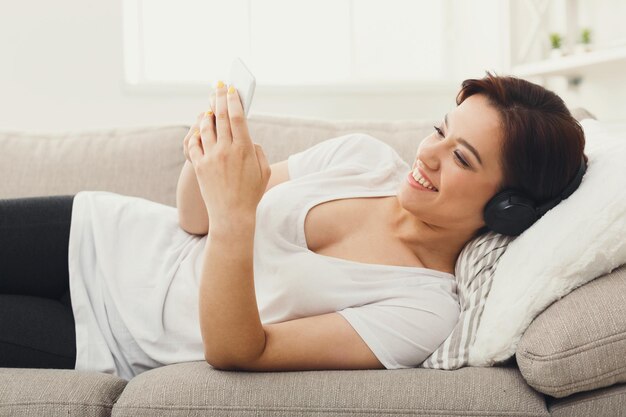 Mujer Joven En Auriculares De Mensajer A En Smartphone En Casa