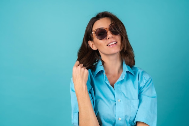 Mujer Joven Con Una Camisa Azul En Una Pared Con Gafas De Sol Posando