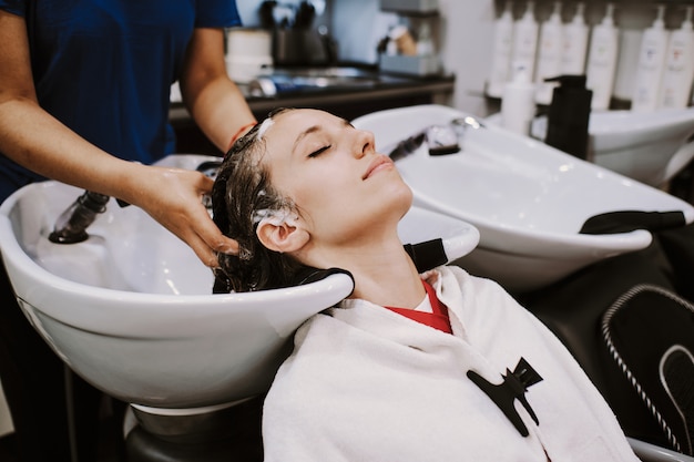 Mujer joven feliz con peluquería lavar la cabeza en ...