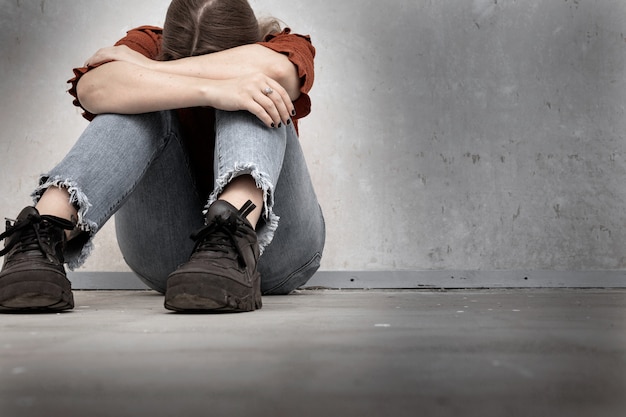 Mujer Joven Llora Y Sentada Cerca De Una Pared Vacia Sola Triste Y Deprimida Nina Sosteniendo Su Cabeza Hacia Abajo Foto Premium