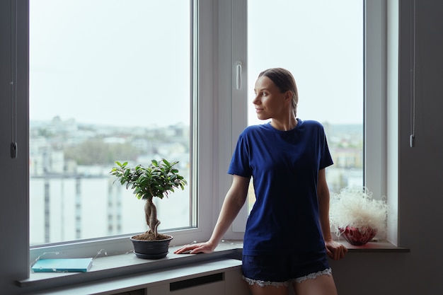 Mujer Joven Mirando Por La Ventana A La Ciudad Foto Gratis