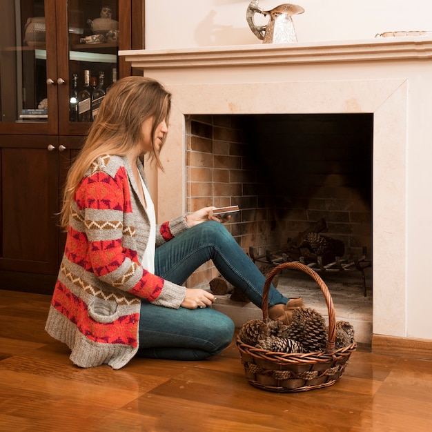 Mujer joven sentada fuera de la chimenea con caja de cerillas y canasta