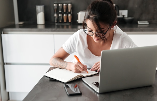 Mujer Joven Seria Concentrada Que Usa Las Notas De La Escritura De La Computadora Portátil 