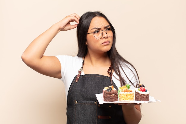 Mujer latina joven que se siente perpleja y confundida rascándose la