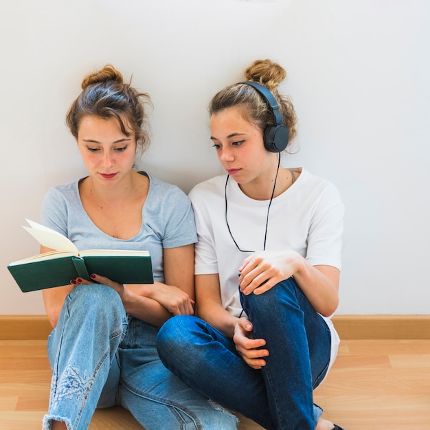 Mujer Mirando A Su Hermana Leyendo El Libro Sentado En El Piso De Madera Foto Gratis 7595