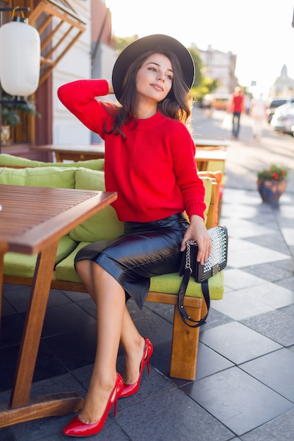 Mujer morena encantadora en suéter hecho punto otoño rojo y falda de