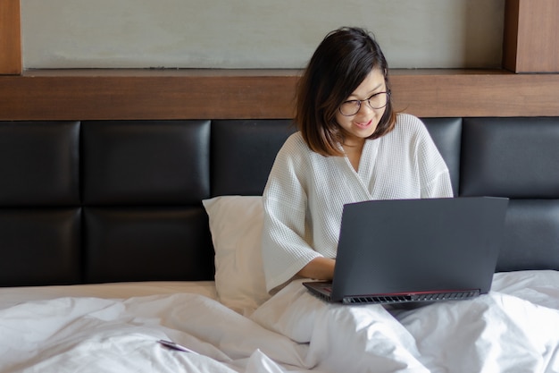 Mujer De Negocios Joven Que Usa La Computadora Portátil En La Cama Mientras Trabaja Desde Casa 