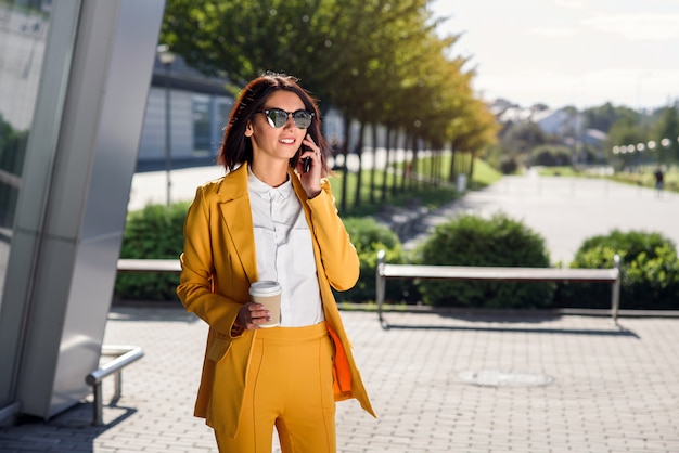 Mujer De Negocios Moderna En Gafas De Sol Y Traje Amarillo Se Encuentra