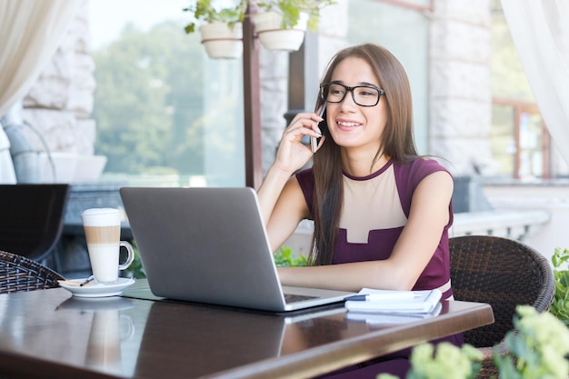 Mujer De Negocios Sonriente Hablando Por Teléfono Y Trabajando En Una Laptop Sentada En El Café 9480