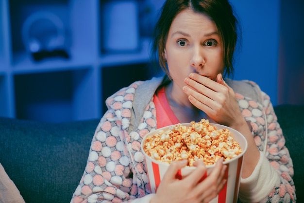 Mujer Con Palomitas De Maíz Sentado En El Sofá Viendo Algo Aterrador