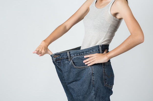 Mujer de pérdida de peso muestra un viejo jeans - Foto Premium