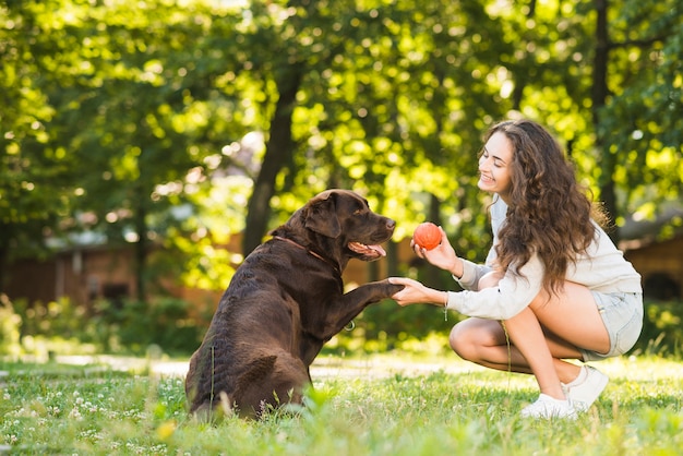 Mujer y perro jugando con la pelota en el parque | Foto Premium