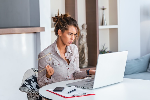 Mujer que trabaja con la computadora portátil en casa expresión ...