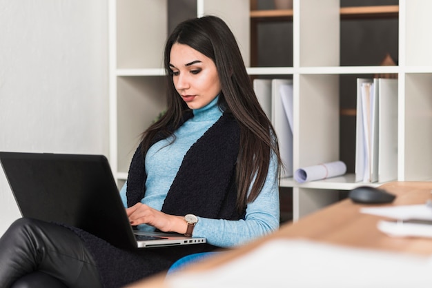 Mujer que trabaja en la computadora portátil en la oficina | Foto Gratis