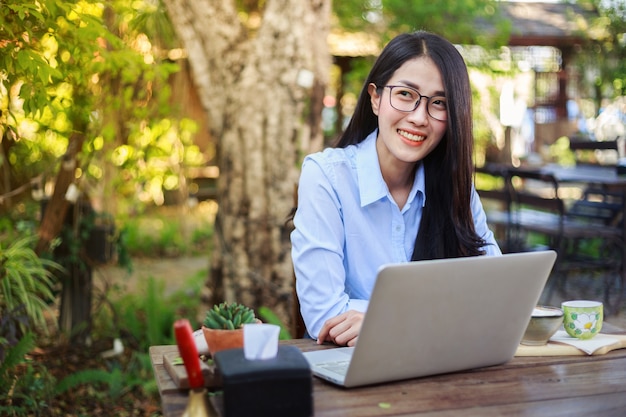 Mujer que usa la computadora portátil y tomando café en el jardín ...