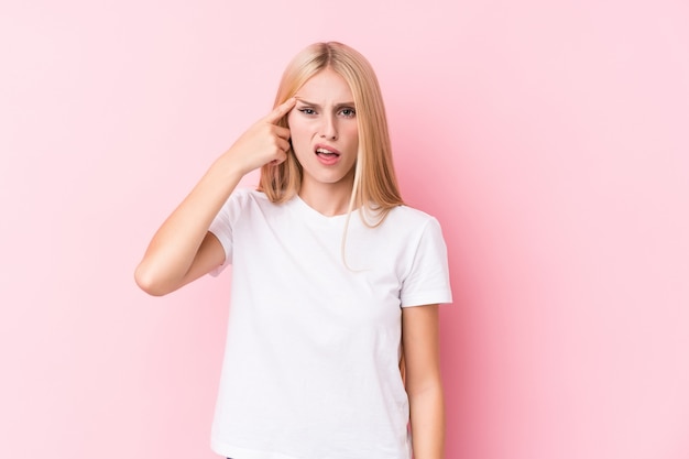 Mujer rubia joven en la pared rosada que muestra un gesto de la decepción con el índice. Foto Premium