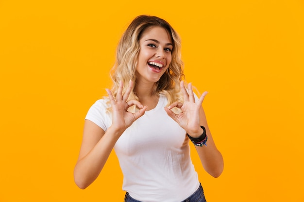 Mujer Rubia En Ropa Básica Sonriendo Y Mostrando El Signo De Ok Aislado Sobre Pared Amarilla 4207