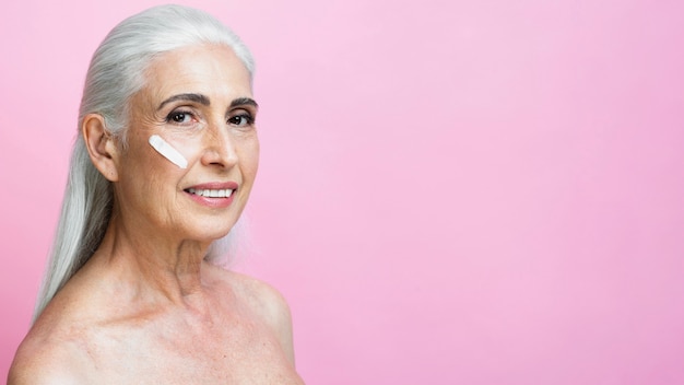 Mujer senior sonriente con tratamiento de cuidado de la piel | Foto Gratis