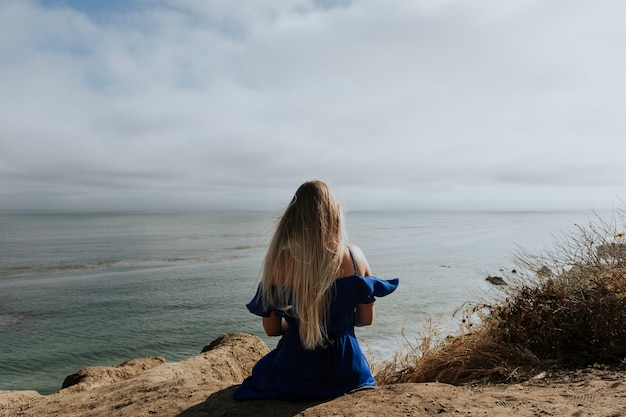 Una Mujer Sentada Sola En La Playa Foto Premium