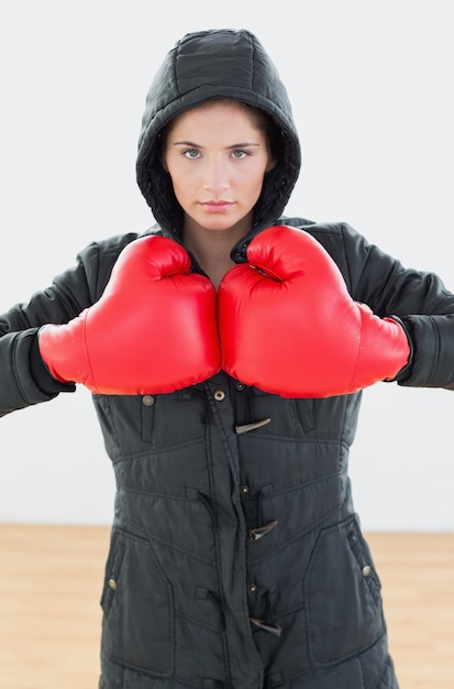 Mujer Seria En Guantes De Boxeo Rojos Y Capucha Negra En El Gimnasio