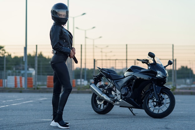 Mujer Sexy Motociclista En Chaqueta De Cuero Negro Y Casco Integral Se Encuentra Cerca De 1143
