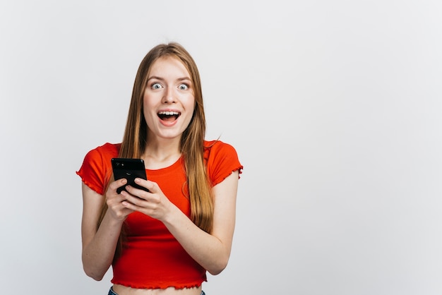 Mujer Sorprendida Sosteniendo Su Teléfono Con Espacio De Copia Foto Gratis