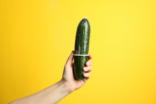 Mujer Sostenga Pepino Con Condón Sobre Fondo Amarillo Espacio Para Texto Foto Premium