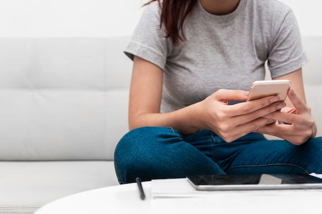 Mujer sosteniendo un teléfono inteligente mientras trabajaba en su casa Foto gratis