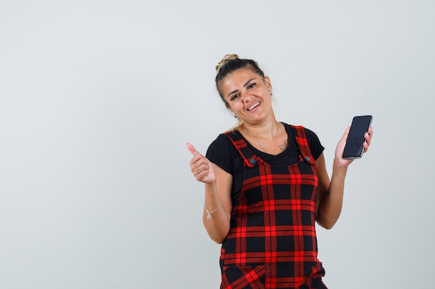 Mujer Sosteniendo Teléfono Móvil Mostrando El Pulgar Hacia Arriba En Vestido Delantal Y Mirando 4976