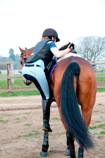 Mujer subiendo a un caballo | Foto Premium