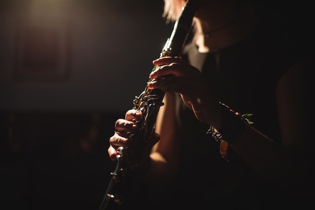 Mujer tocando un clarinete en la escuela de música Foto gratis