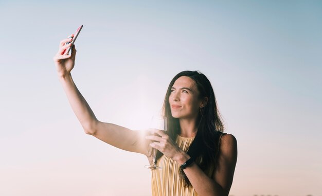 Mujer tomando selfie en la luz del sol Foto gratis