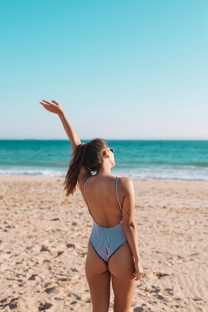 Mujer En Traje De Bano Agitando La Mano En La Playa Foto Gratis