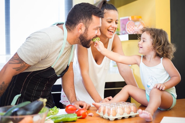 Mujer viendo hija alimentando pimiento a su padre Foto gratis