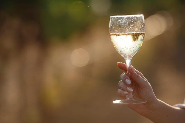 Mujer viticultor degustación de vino blanco de una copa en un viñedo