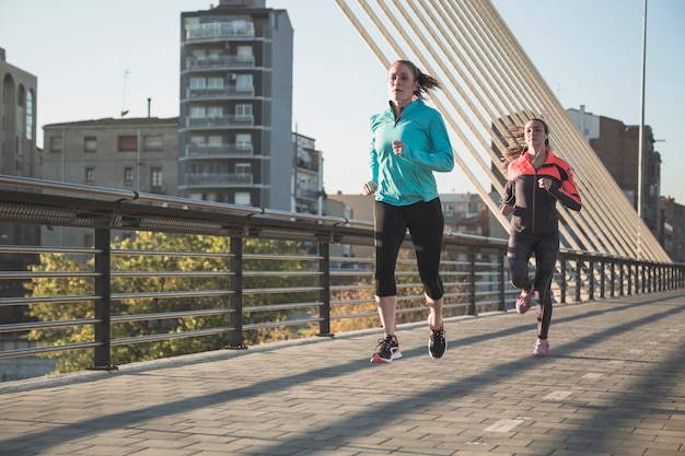 Mujeres jóvenes corriendo con la ciudad de fondo | Foto Gratis