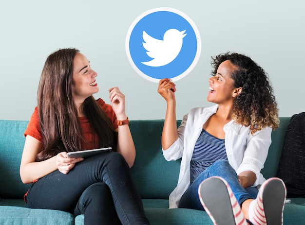 Mujeres jóvenes mostrando un icono de twitter Foto gratis