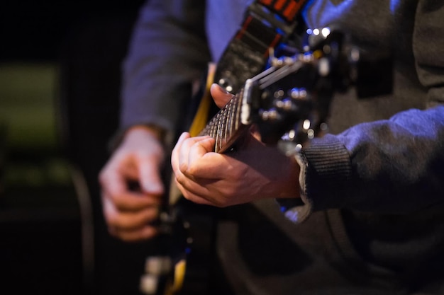 Músico en club nocturno - guitarrista sosteniendo la caja de resonancia