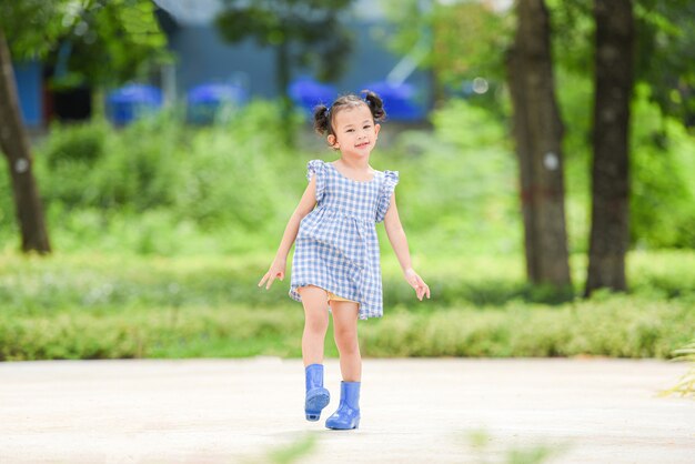 Niña asiática feliz en el fondo del árbol del jardín del parque niño