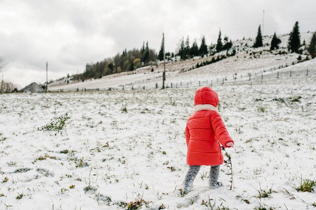 Niña camina de regreso a la montaña nevada naturaleza de invierno