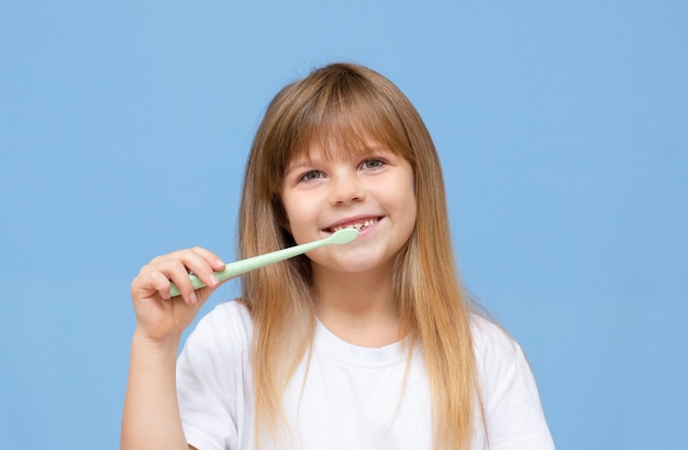 Niña Feliz Cepillándose Los Dientes Con Un Cepillo De Dientes Y Sonriendo Sobre Un Fondo Azul 7011